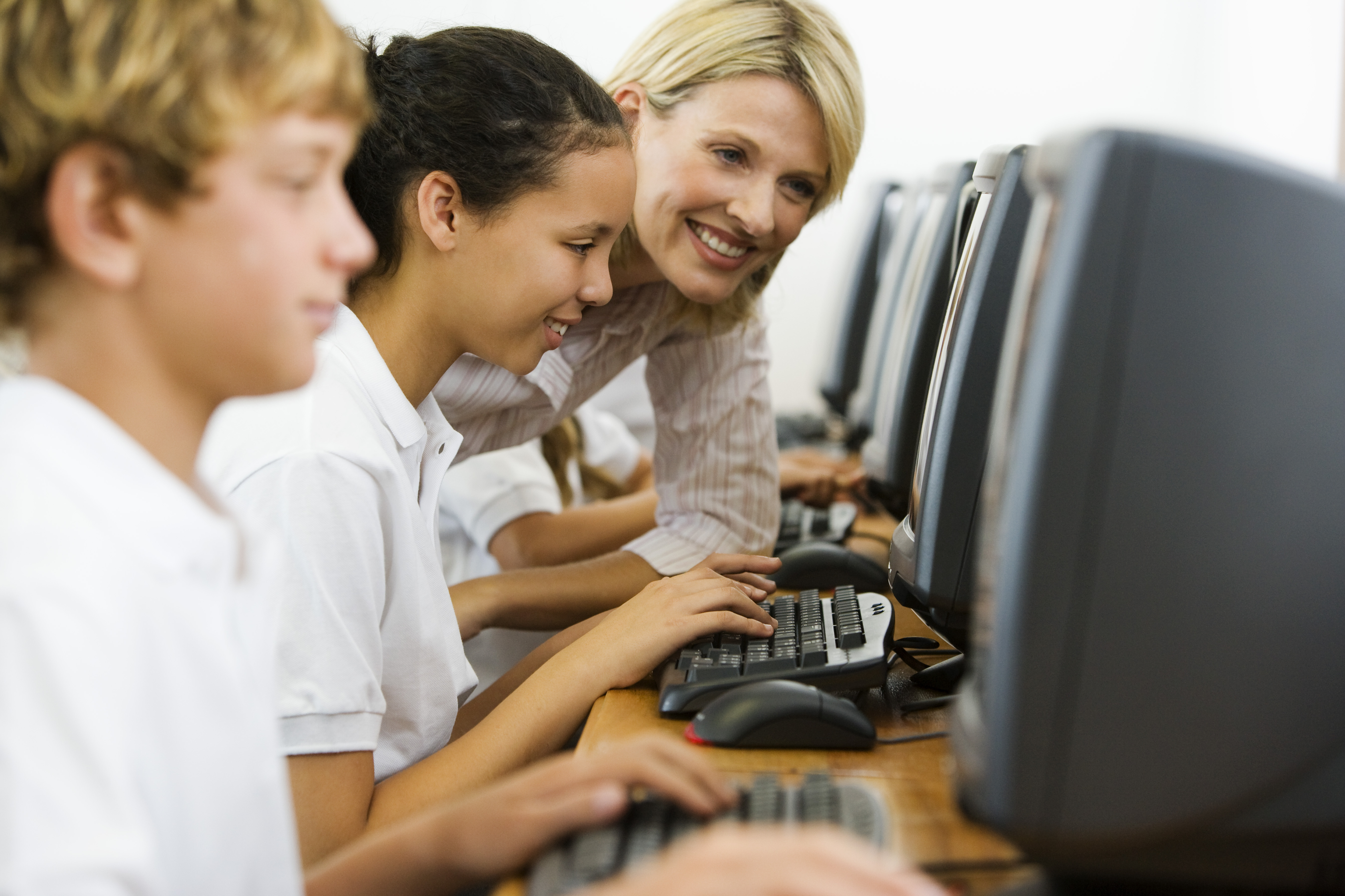Photo of teacher helping students use computers via freeimages.com